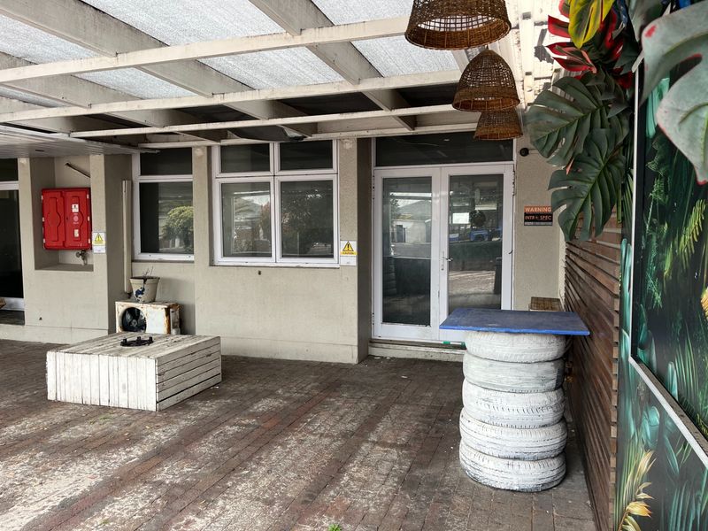 Covered outdoor patio area featuring brick paving, timber wall cladding, and direct access to the restaurant interior through glass doors.