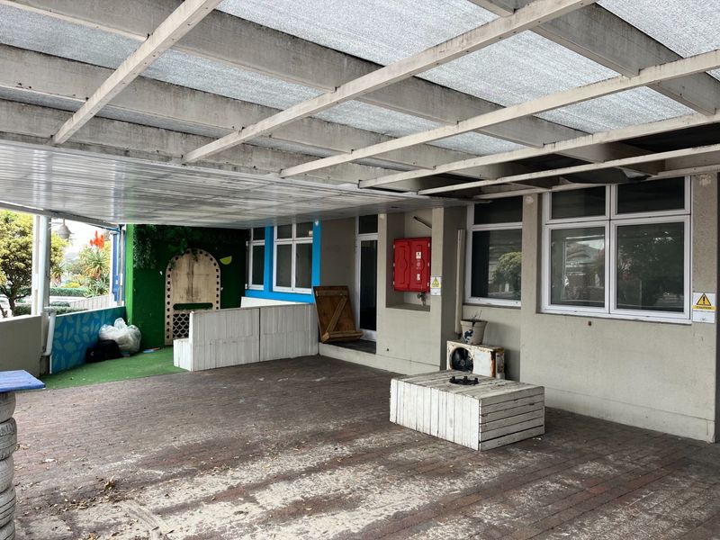 A covered outdoor patio area featuring paved flooring and a timber pergola structure, suitable for restaurant seating or an entertainment space.