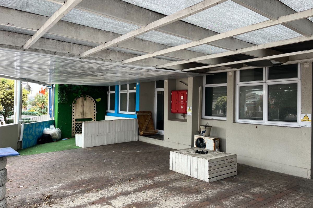 A covered outdoor patio area featuring paved flooring and a timber pergola structure, suitable for restaurant seating or an entertainment space.