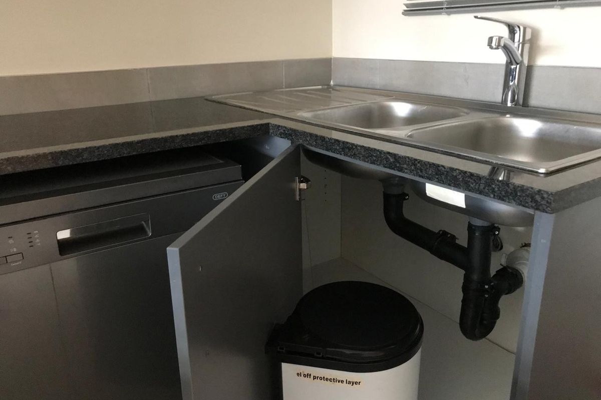 Kitchen area featuring a double bowl stainless steel sink, chrome mixer tap, granite-look countertop, and integrated dishwasher.