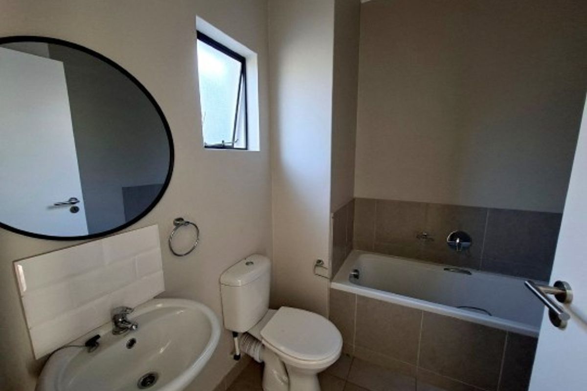 A clean, functional bathroom featuring a pedestal basin, a built-in bathtub with tiled surround, and a standard toilet.