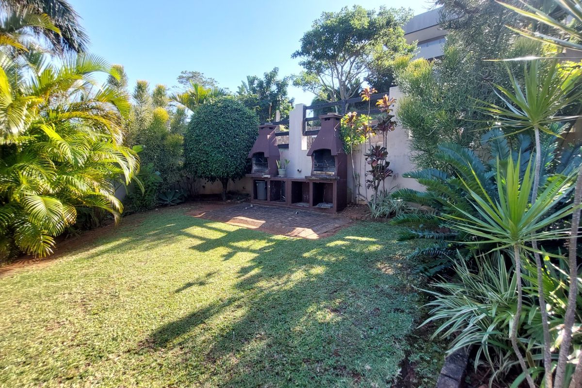 A private rear garden featuring a built-in brick braai area, established landscaping, and a lawn, providing a functional outdoor entertainment space.