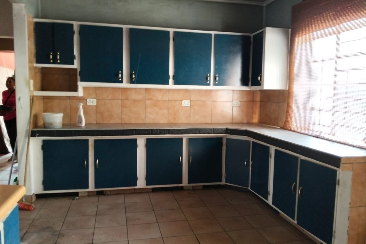 A dated kitchen featuring L-shaped cabinetry, tiled backsplash, and tiled flooring, offering a blank canvas for a modern renovation.