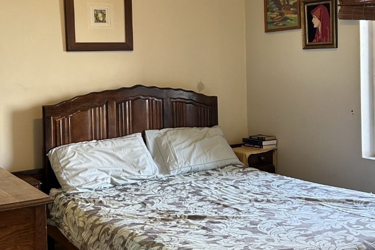 A standard bedroom featuring neutral walls, a window with a bamboo blind, and a curtain rod.