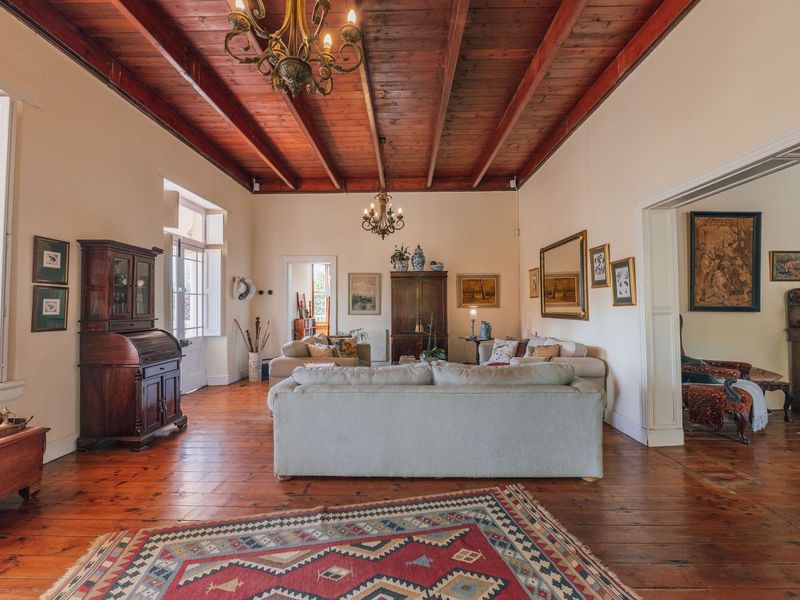 Spacious living room featuring high exposed timber beam ceilings, polished hardwood flooring, and classic timber window shutters, offering a warm and traditional aesthetic.