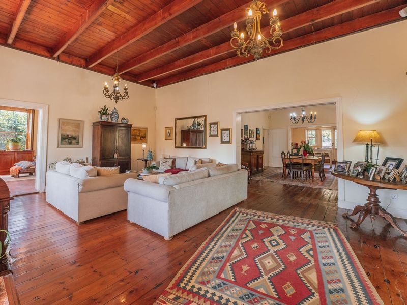 Spacious open-plan living and dining area featuring high exposed timber beam ceilings and original hardwood flooring, creating a warm and character-filled atmosphere.