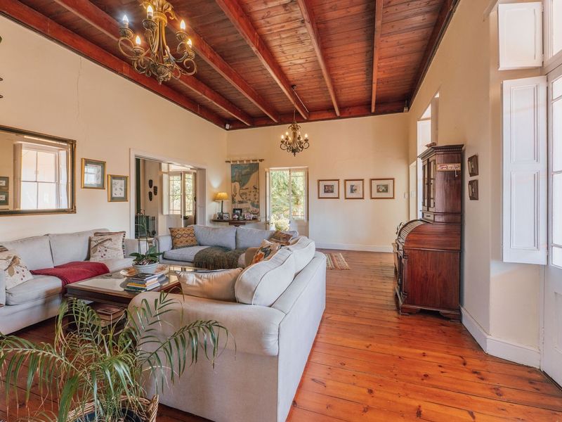 Spacious living room featuring high exposed timber beam ceilings, polished hardwood floors, and classic french doors leading to the exterior.