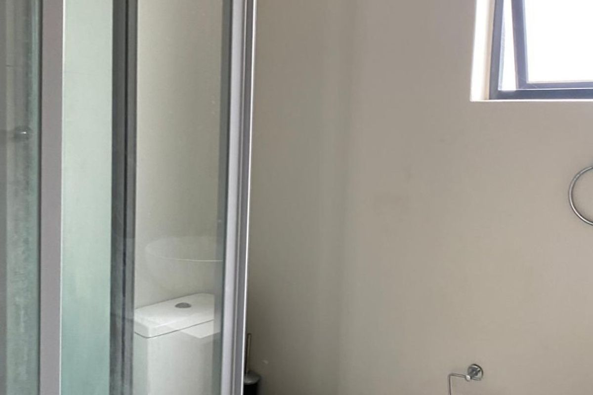 A compact bathroom featuring a shower enclosure, a standard toilet, and a top-hung window, providing essential functional fixtures.