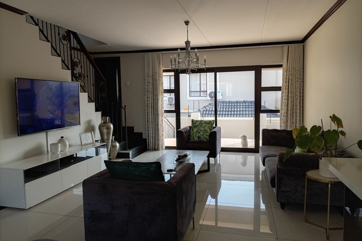 Spacious living room featuring polished tiled flooring, a wrought iron staircase, and large sliding glass doors providing natural light and access to the exterior.