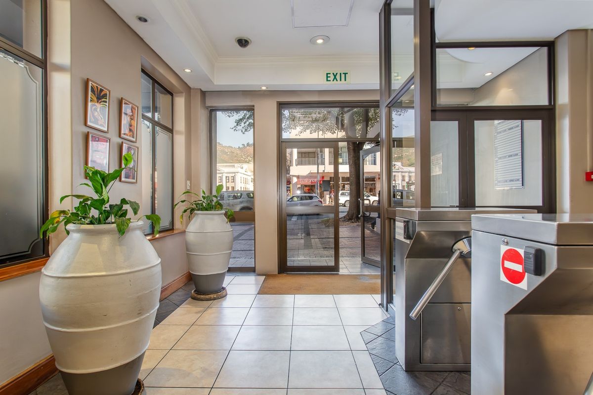 Commercial building entrance lobby featuring tiled flooring, glass doors, and a secure turnstile access point.