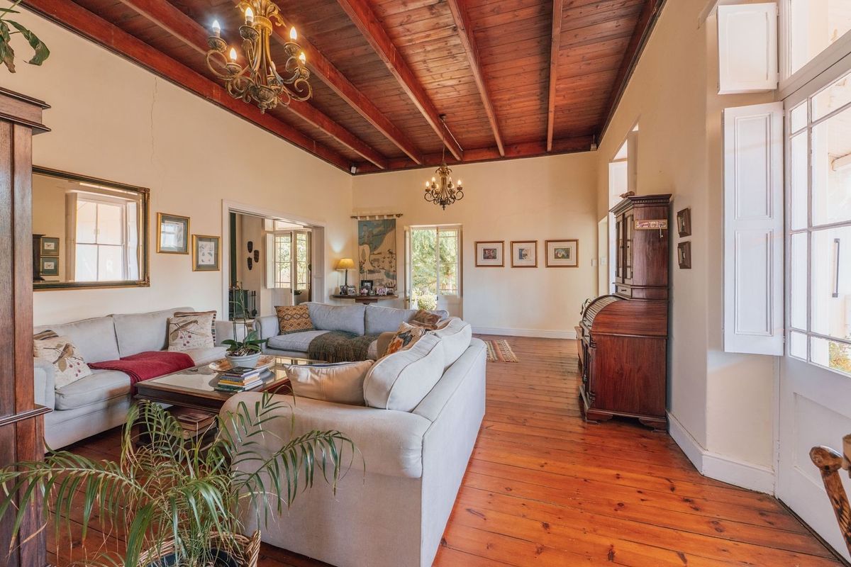 Spacious living room featuring high exposed timber beam ceilings, polished hardwood flooring, and classic french doors leading to the exterior.