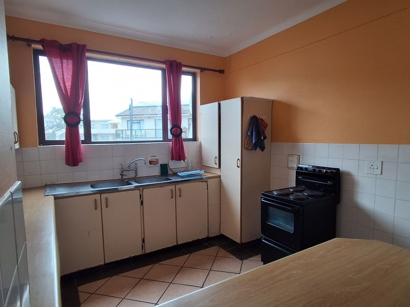 A functional kitchen featuring built-in cabinetry, a double sink, tiled splashbacks, and a freestanding stove, offering potential for modernization.