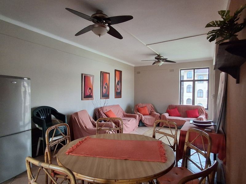 Open-plan living and dining area featuring tiled flooring and dual ceiling fans, providing a functional space for relaxation and meals.