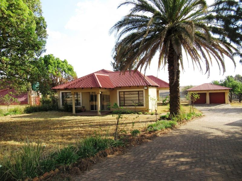 Front view of a small holding property featuring a main dwelling with a covered patio, a detached garage, and a paved driveway.