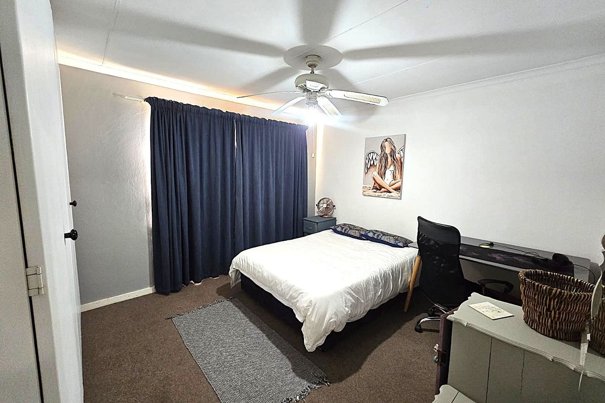 A functional bedroom featuring carpeted flooring and a ceiling fan, providing a comfortable and practical living space.