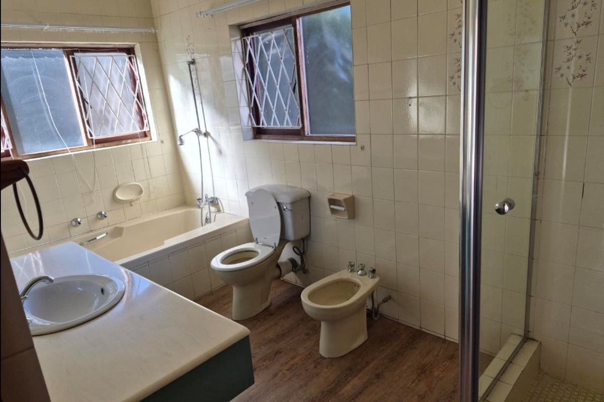 A spacious, dated bathroom featuring a built-in bathtub, separate shower enclosure, toilet, bidet, and a vanity basin with tiled walls.