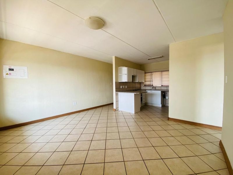 An open-plan living and kitchen area featuring tiled flooring, built-in cabinetry, and a functional layout, ready for modernization and personal styling.