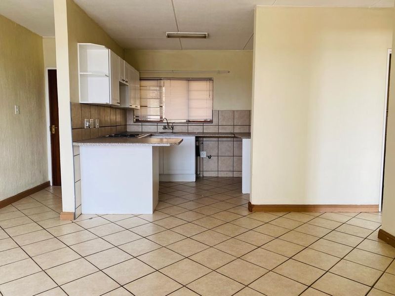 A functional kitchen featuring tiled flooring, built-in cabinetry, a stainless steel sink, and a tiled backsplash, offering a clean and practical layout.