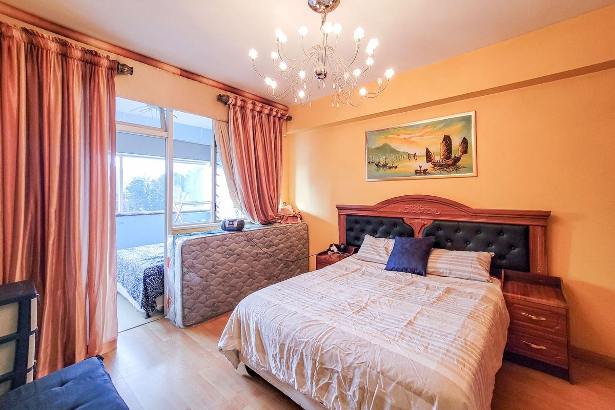 A bedroom featuring laminate flooring, a central chandelier, and a sliding glass door providing access to an adjoining balcony area.