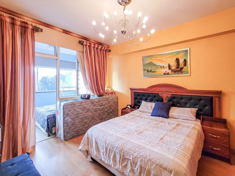 A bedroom featuring laminate flooring, a central chandelier, and a sliding glass door providing access to an adjoining balcony area.