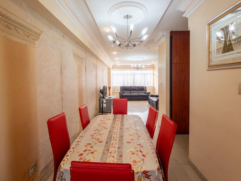 Open-plan living and dining area featuring decorative ceiling roses, coved cornicing, and tiled flooring, offering a spacious layout for entertaining.