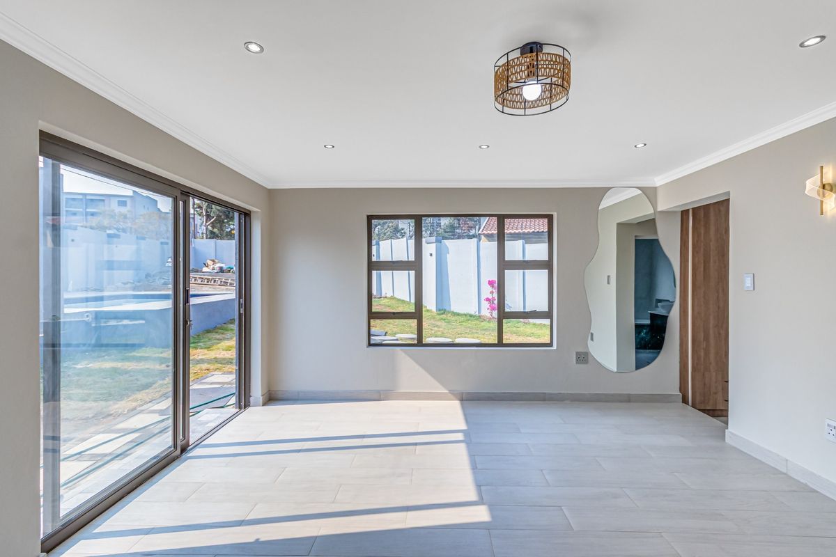 Bright and spacious living area featuring large sliding glass doors, modern tiled flooring, recessed downlights, and neutral wall finishes.
