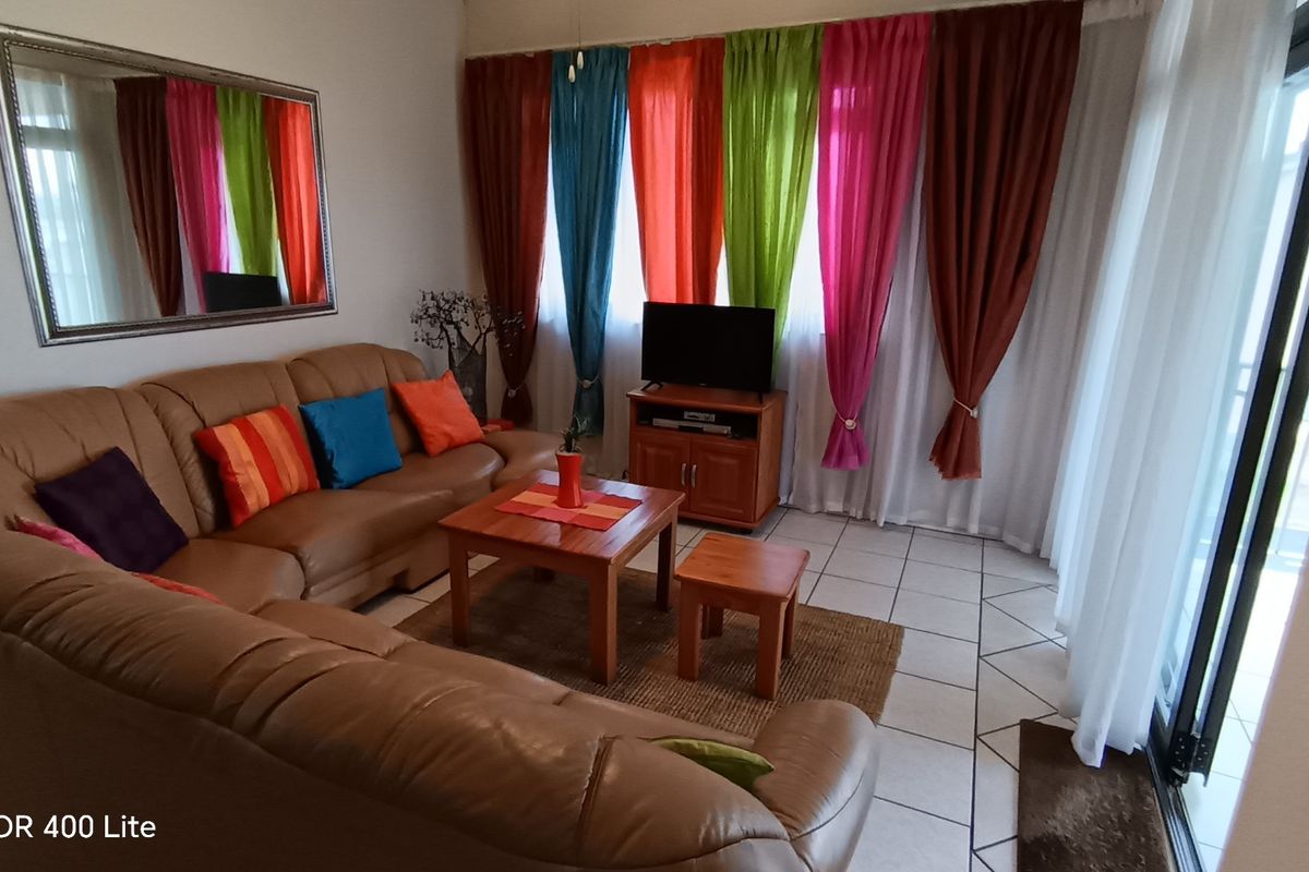 A living room area featuring tiled flooring and a sliding glass door providing access to an outdoor space.