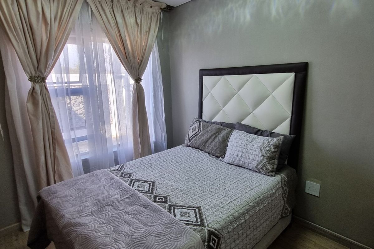 A well-maintained bedroom featuring laminate flooring, a built-in wardrobe, and neutral wall finishes, providing a comfortable and functional living space.