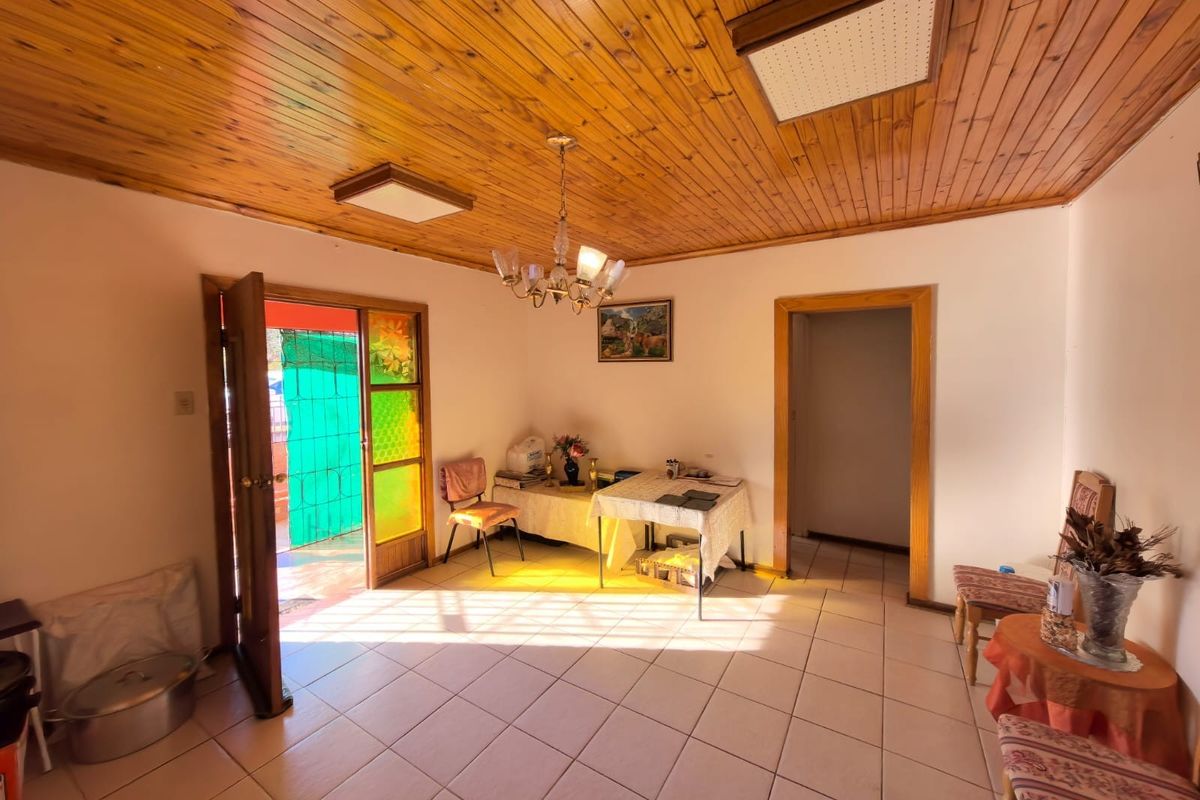 A living area featuring ceramic floor tiles and a timber tongue and groove ceiling, with direct access to an outdoor space.