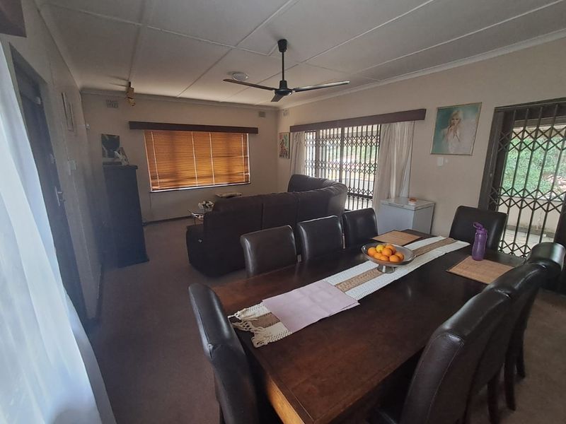 Open plan living and dining area featuring a ceiling fan, security gates on windows and doors, and neutral wall finishes.