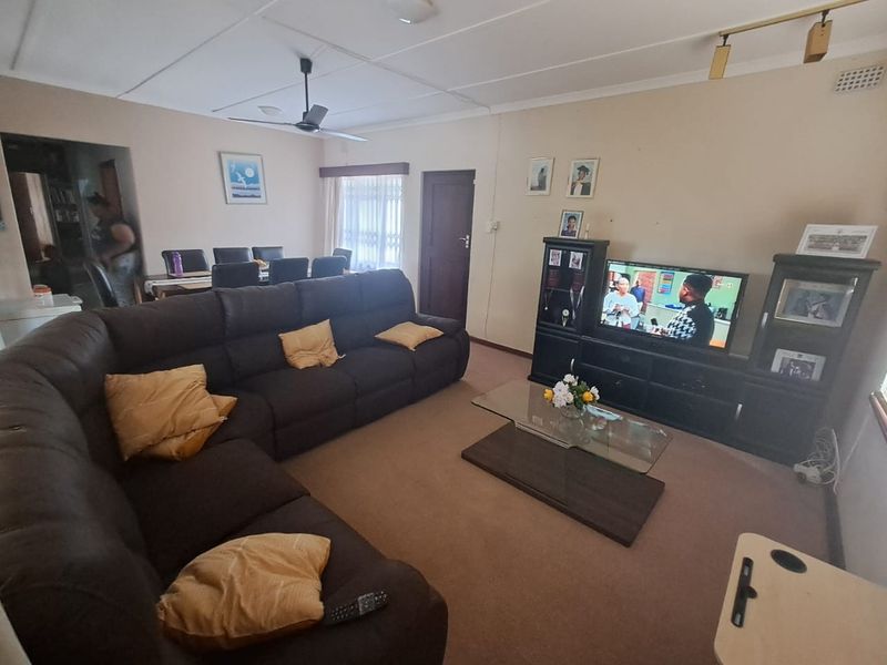 Open plan living and dining area featuring neutral wall tones, carpeted flooring, and a ceiling fan, providing a functional and comfortable family space.