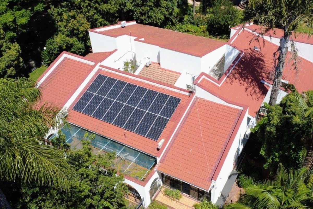Aerial view of the property featuring a well-maintained tiled roof, integrated solar panel array, and a glass-roofed conservatory section.