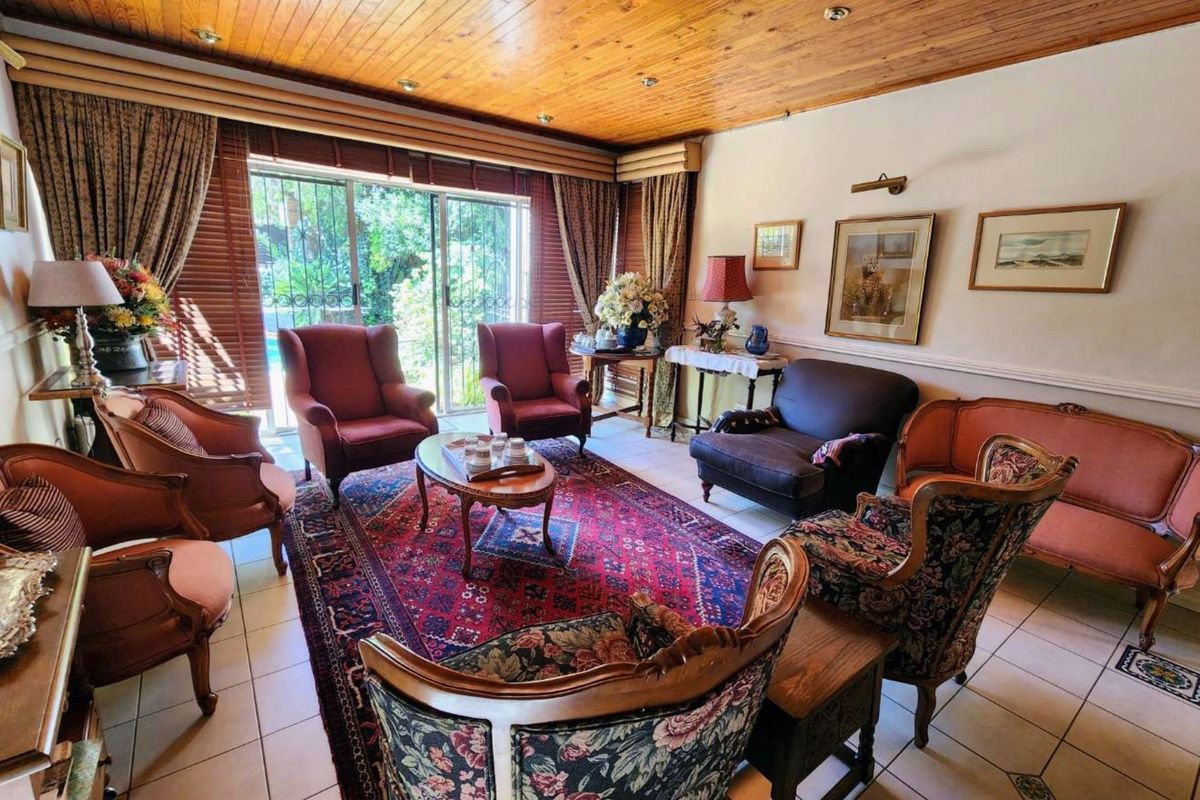A traditional living room featuring a warm timber-clad ceiling, recessed lighting, and large sliding glass doors that provide access to the outdoor area.