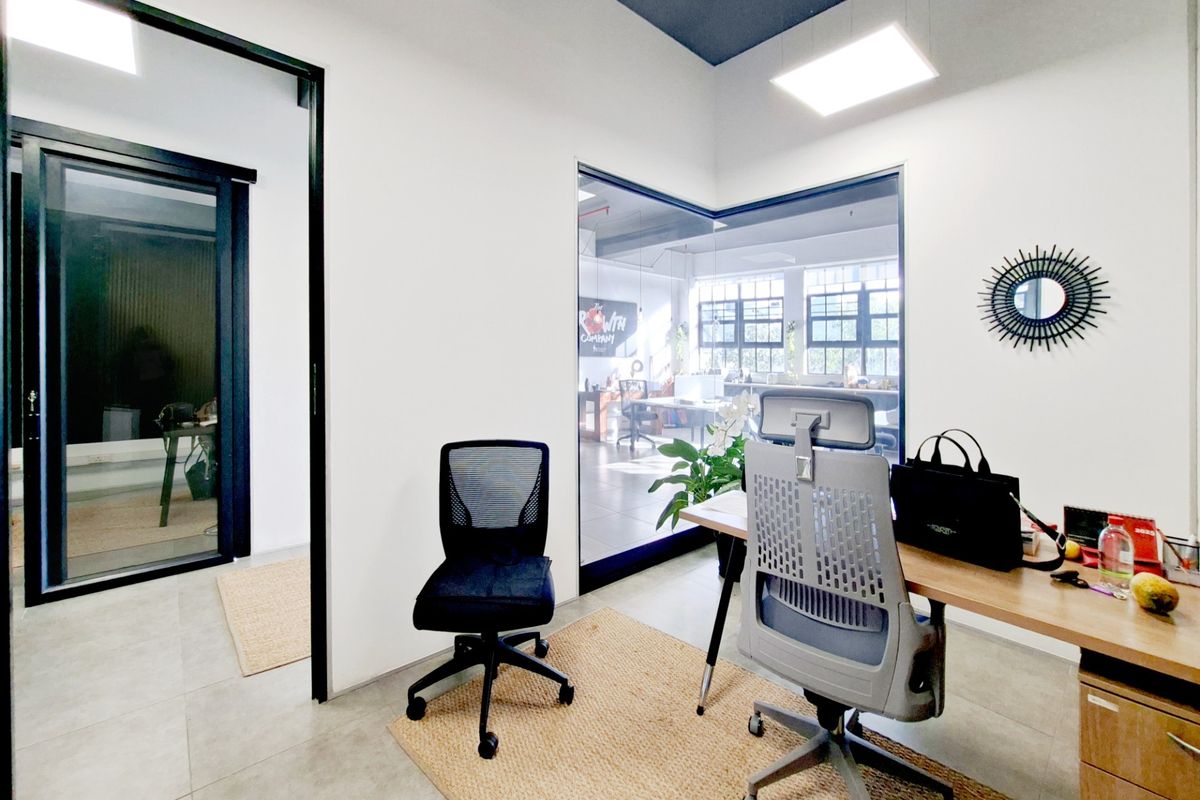 Modern office space featuring glass partition walls, sleek black door frames, recessed ceiling lighting, and high-quality tiled flooring.