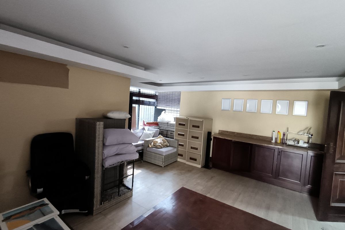 A spacious living area featuring built-in cabinetry, recessed ceiling lighting, and a combination of timber and tiled flooring.