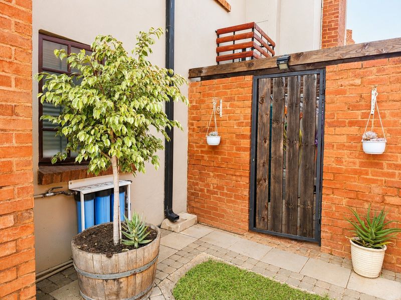 A private rear courtyard featuring a brick wall, timber gate, and a wall-mounted water filtration system, providing a functional and secure outdoor space.
