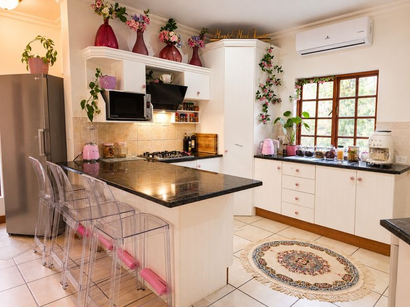 A well-maintained kitchen featuring granite countertops, white cabinetry, a gas hob, built-in microwave, and a split-system air conditioner.