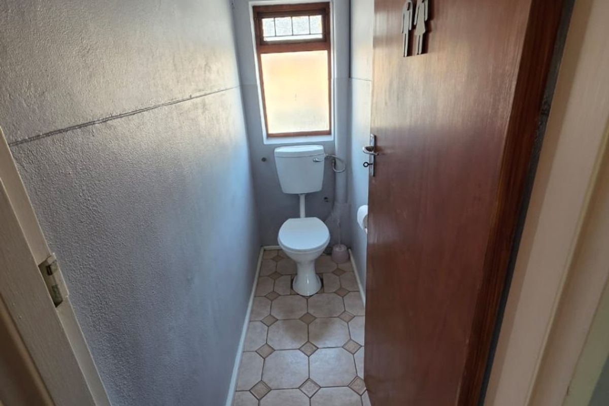 A compact, functional guest toilet featuring tiled flooring and a window for natural light and ventilation.
