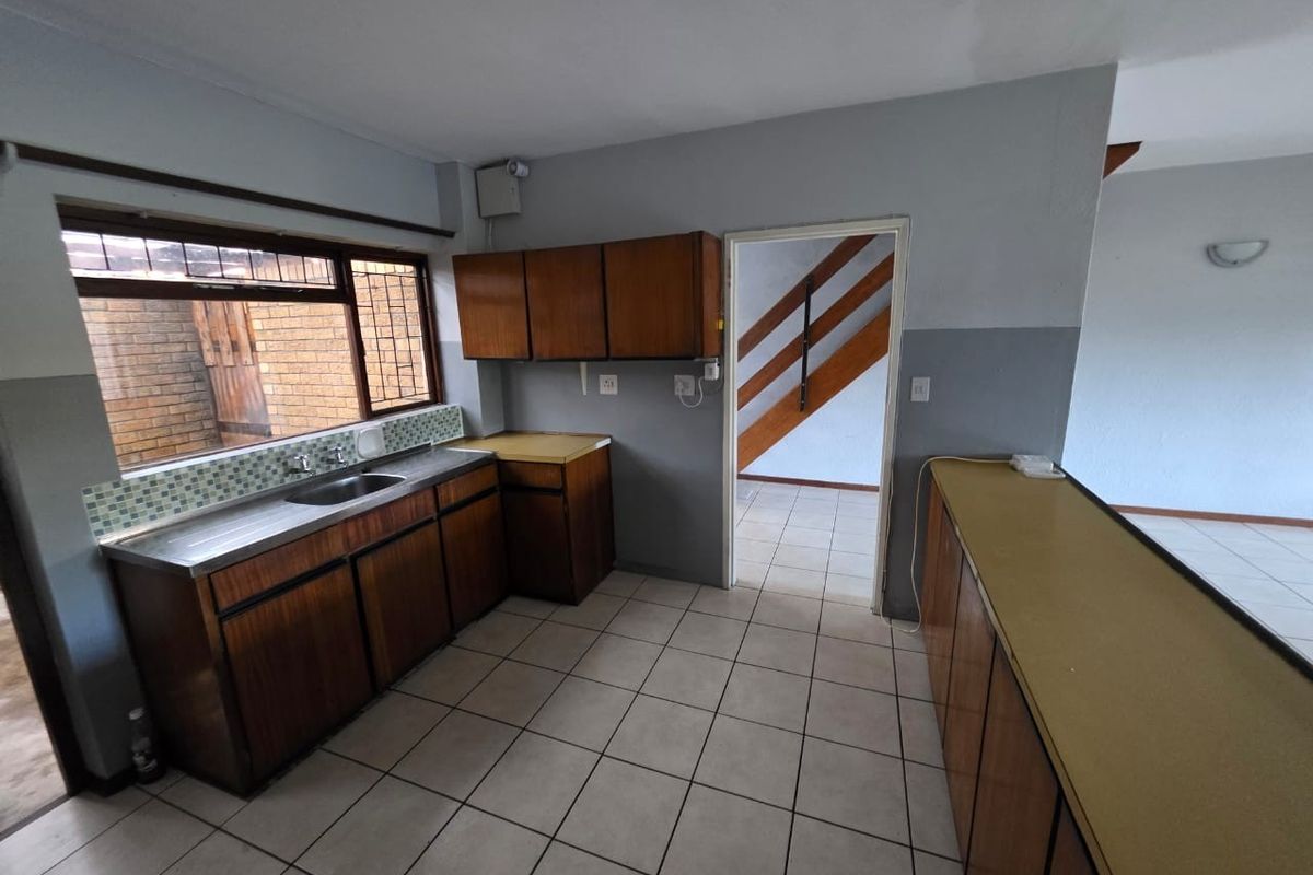 A functional kitchen space featuring built-in wooden cabinetry, a stainless steel sink, and a breakfast bar, ready for modern updates.