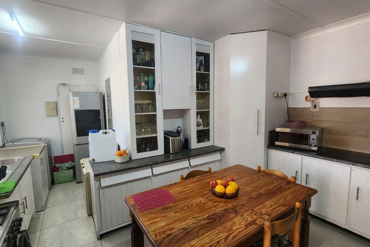 Functional kitchen featuring built-in cabinetry, laminate countertops, and an extractor fan, offering a practical layout with space for a dining table.