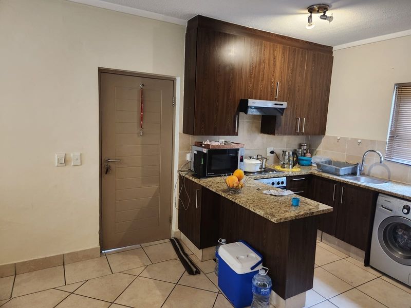 A functional kitchen featuring dark wood cabinetry, granite countertops, a tiled backsplash, and integrated appliances, offering a practical layout for daily use.
