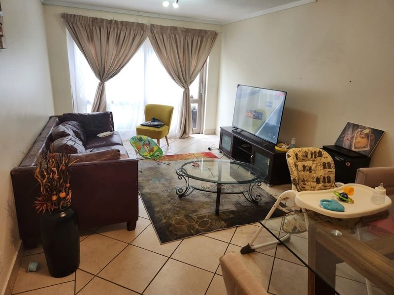 A living room featuring tiled flooring and a sliding glass door leading to an outdoor area, providing natural light to the space.