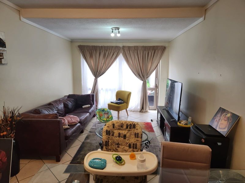 A functional living room featuring tiled flooring and a sliding glass door providing access to the outdoor area.