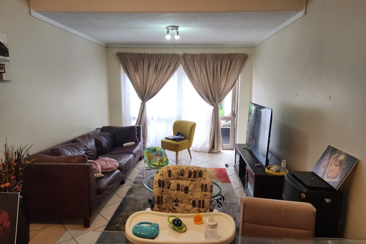 A functional living room featuring tiled flooring and a sliding glass door providing access to the outdoor area.