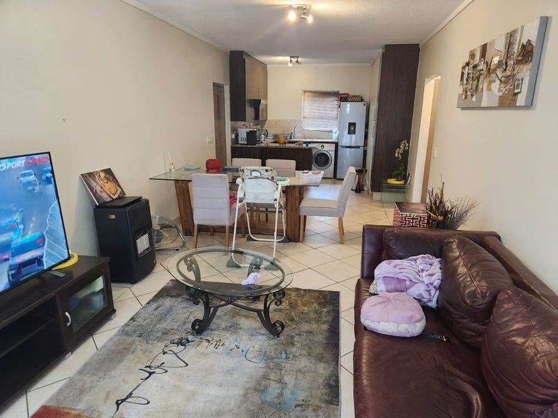 Open-plan living and dining area featuring tiled flooring and an integrated kitchen space with built-in cabinetry.