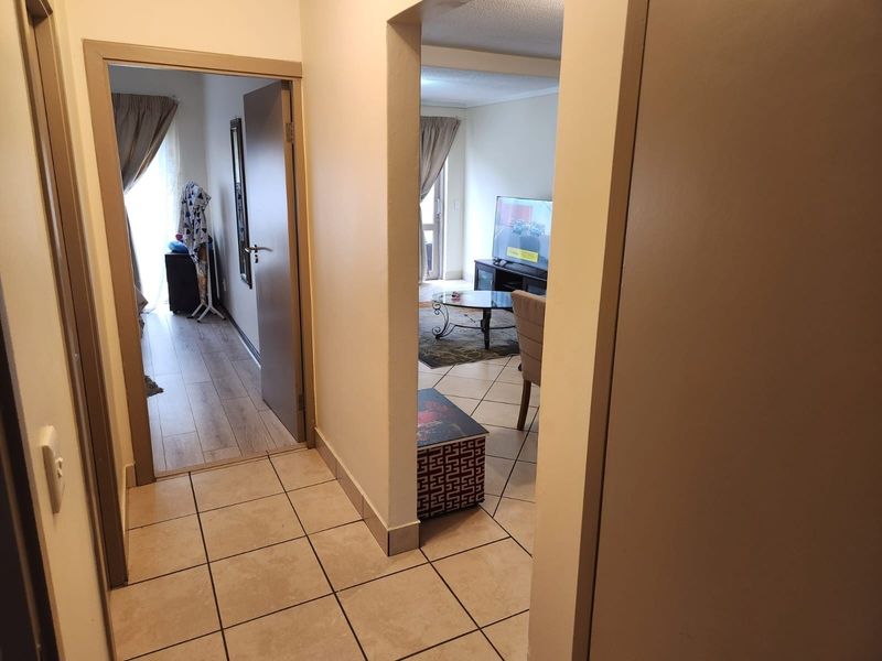 A functional hallway area featuring tiled flooring, providing access to the living room and adjacent bedroom.