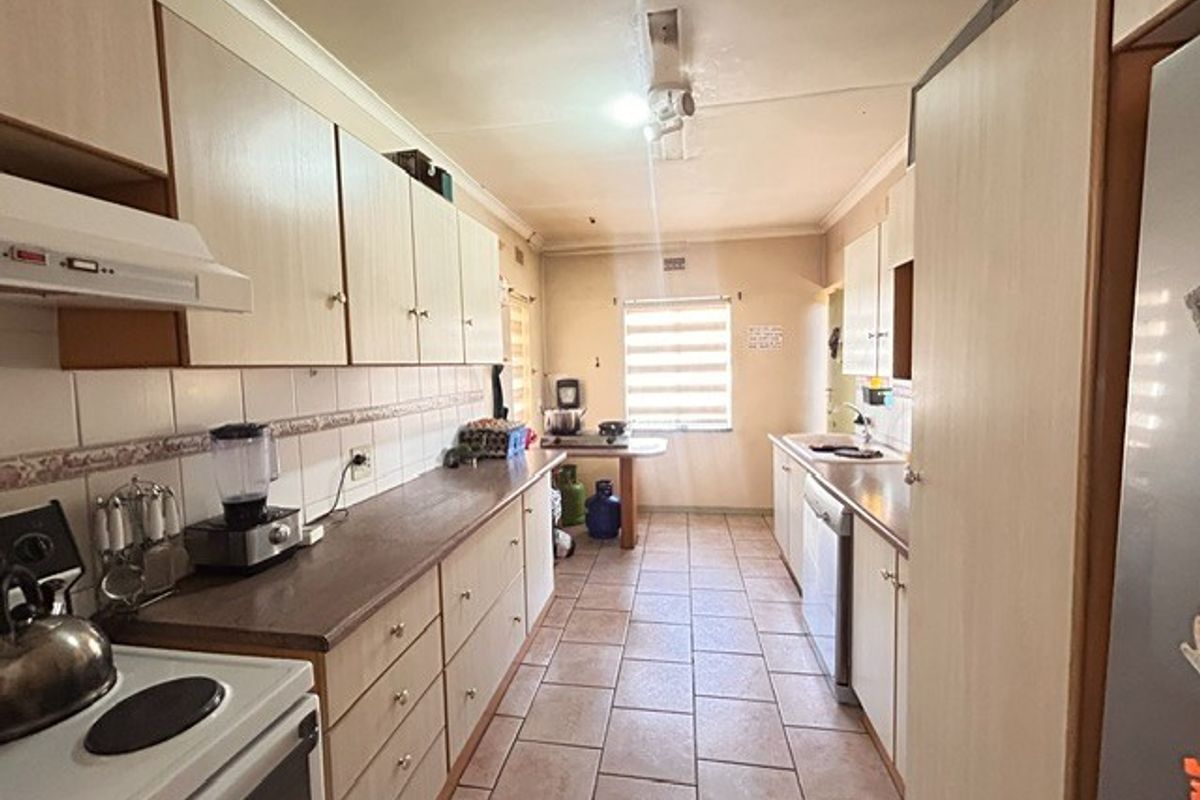 A functional galley-style kitchen featuring laminate cabinetry, tiled flooring, and a built-in oven, offering a practical layout with ample storage space.