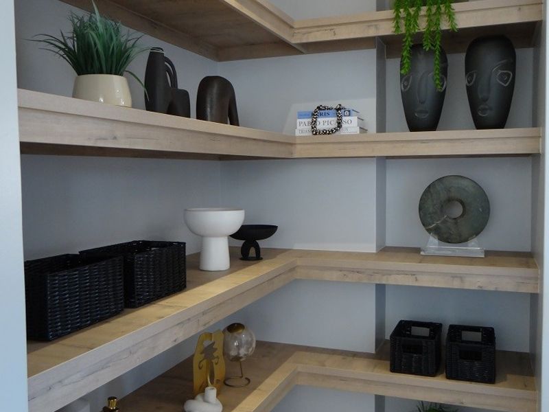 A well-organized pantry or scullery area featuring custom built-in timber corner shelving and modern tiled flooring.