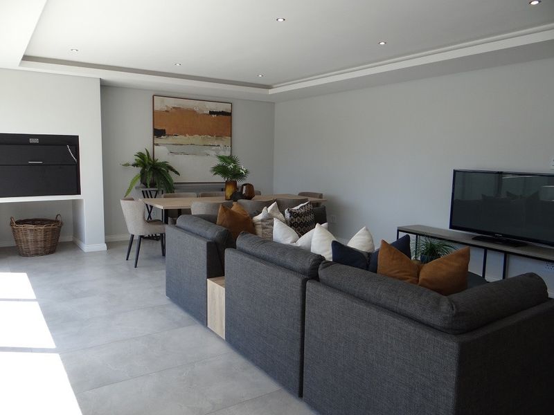 Spacious open-plan living and dining area featuring modern tiled flooring, recessed ceiling lighting, and a built-in fireplace.