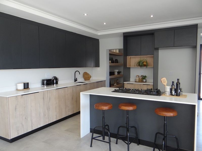 Modern kitchen featuring two-tone cabinetry, quartz countertops, a central island with a gas hob, and an adjacent scullery area.
